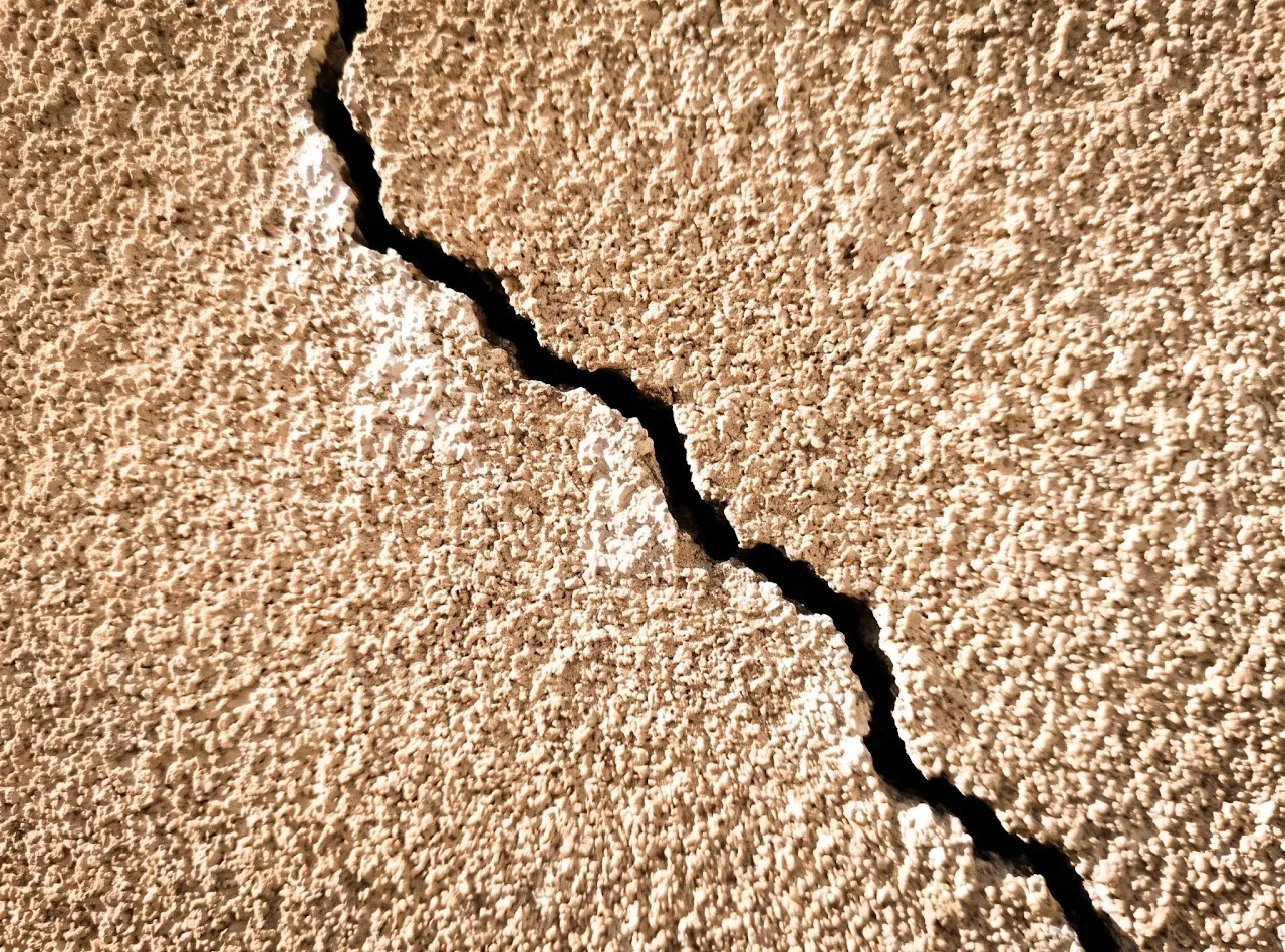Gros plan sur une fissure dans un enduit, sans aucun repère ni échelle.