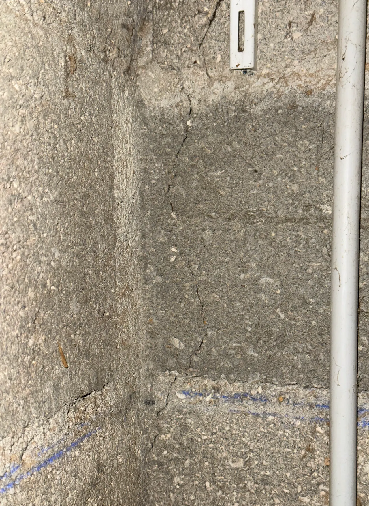 Angle de mur intérieur en parpaings, avec une fissure qui le traverse.